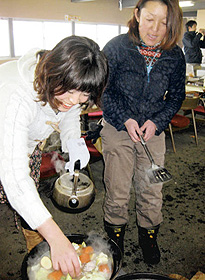ダッチオーブンを使った料理を指導する自然学校スタッフの高橋諭子さん（右）と参加者