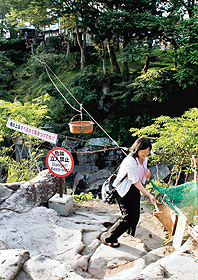 木づちで板をたたき、空飛ぶ団子を注文する観光客＝岩手県一関市で