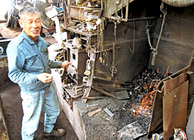 ふいごを動かし炎を上げる鍛冶工房の小藤洋也さん＝同県安来市で