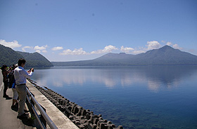 透明度の高い、青く澄んだ支笏湖。前方の右端が風不死岳、その左に樽前山が見える＝北海道千歳市で