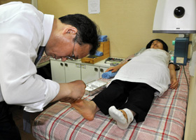 はり治療をする韓方医の辛東勲さん（左）＝韓国の釜山市で