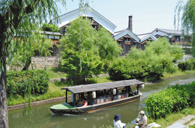 爽やかな風の中、酒蔵沿いをゆっくりと進む十石舟。川岸ではスケッチを楽しむ人の姿があった＝いずれも京都市伏見区で
