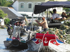 メコンデルタの食の恵みを積んだ船が行き交うカイランの水上市場。パイナップルは船から船へと器用に投げ渡されていた＝ベトナム南部のカントーで