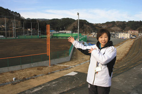 防潮堤で新しくできた野球場について語る学ぶ防災ガイドの元田久美子さん＝岩手県宮古市で