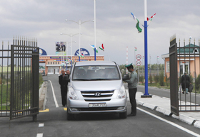 国境を越えてウズベキスタンに車で入国する人たち。奥はタジキスタンの国境検問所＝サマルカンドで