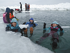 浮力が強く、温かいドライスーツを着て、流氷の海で浮かぶ流氷ウオークの参加者＝北海道斜里町で