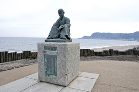 大森浜の啄木小公園にある石川啄木の像。奥の立待岬の近くには啄木一族の墓がある＝いずれも北海道函館市で