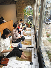 薬茶房ポムドンで思い思いの足湯に漬かる女性たち＝いずれも韓国・ソウルで
