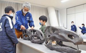 化石発見のたびに変化するフクイサウルスの頭骨を子どもたちに説明する柴田主任研究員（左から２人目）＝勝山市の県立恐竜博物館で