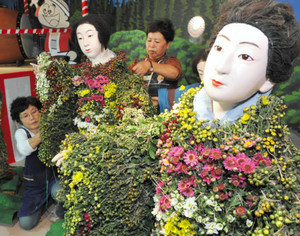 色とりどりの花が丁寧に飾り付けられていく菊人形＝飯田市の元善光寺で