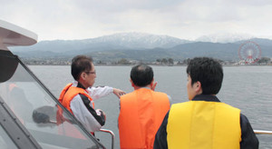 船上から立山連峰や海岸の町並みを望む乗船者たち＝富山湾で