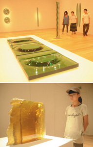 （上）不思議な凹凸や光の反射が楽しめる家住利男さんの作品（下）前に進む女性像が浮かび上がる作品「アンダンテ」を鑑賞する来館者＝いずれも富山市ガラス美術館で