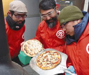 イワシを使った新作ピザの試作品（右）を焼き上げるチーム能登喰いしん坊のメンバー＝穴水町で