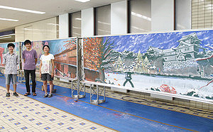 閉校した小学校の黒板にチョークで金沢の四季を描いた（左から）千川岳志さん、栄長義雄さん、伊藤真里奈さん＝金沢駅東もてなしドーム地下広場で