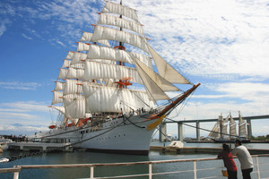 新湊大橋をバックに帆を広げる海王丸。周辺ではさまざまなイベントが計画されている＝射水市で