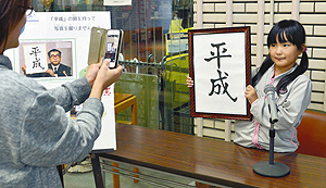 「平成」と書かれた書を手に記念撮影をする親子＝豊橋市中央図書館で
