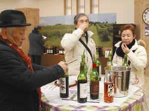 能登ワインの商品を試飲する首都圏からのツアー客ら＝穴水町旭ケ丘で