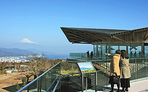 日本平夢テラスの展望回廊から富士山を望む人たち。右は展望施設