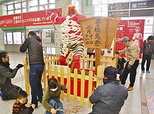 改札前で赤鬼の人形を設置する鬼祭り関係者＝豊橋駅で