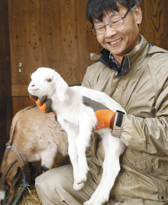 生まれたばかりの雌ヤギ「ももこ」を紹介する橋爪和夫さん＝のと里山海道別所岳サービスエリアで
