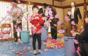 柳の枝に造花の桜をくくり付ける会員や家族＝輪島市河井町で
