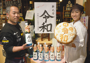 「令和」をデザインした焼酎とパンをＰＲする豊岡さん（左）と伊佐治さん＝中津川市千旦林の観光施設「ちこり村」で