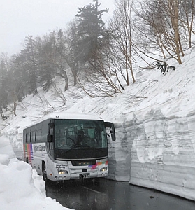 試運転で雪の壁の間を抜けるバス＝松本市安曇で