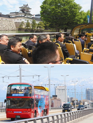 （上）日常とは違った目線から富山城などの景色を楽しむ関係者たち（下）立山連峰を背景に富山大橋を進むオープントップバス＝いずれも富山市で