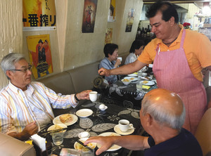 モーニングで客にコーヒーのおかわりをつぐ、店長のアローラさん（右）＝名古屋市港区で