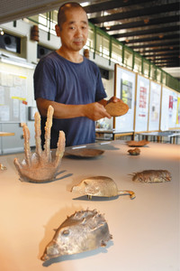 学生が生型鋳造法で作ったオブジェを説明する三船温尚教授＝富山大芸術文化学部で