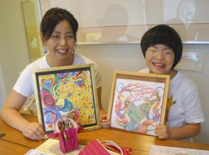 動物などの塗り絵を笑顔で披露する菱田美和さん（右）、母美歌さん＝岐阜市のしあわせおやつ工房ひろがるで