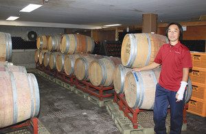 「スイス村ワイナリー」の内方知春さんと、ワインを熟成中の樽＝安曇野市で
