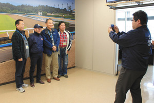 ミルコ・デムーロ騎手（左から２人目）と写真を撮る参加者たち＝いずれも滋賀県栗東市の栗東トレーニングセンターで