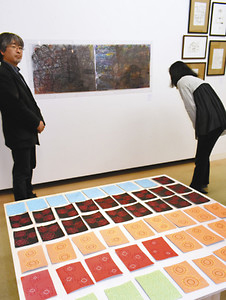 今回、初めて発表された作品が並ぶ展示。作品を解説する米田昌功さん（左）＝高岡市美術館で