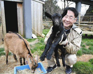 生まれたてのアンコを抱き上げる橋爪和夫さんと、隣で餌を食べるアズキ＝別所岳サービスエリアで