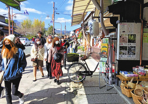 マスク姿の観光客が目立つ嵐山商店街。右に張られているのがキャンペーンのポスター