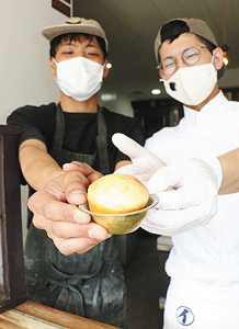 真ちゅう製の器にのせたメロンパンをＰＲする若井夏輝さん（右）と荒谷崇志さん＝金沢市寺町で