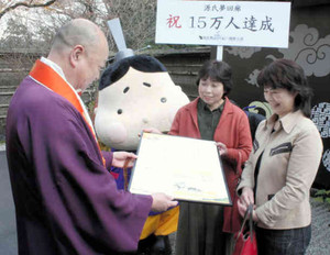 鷲尾遍隆座主（左）から来場１５万人目の記念品を受ける根来洋子さん（右）と井山孝子さん＝大津市石山寺で 