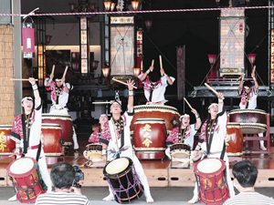 キリコを背に太鼓を演奏する「輪島・和太鼓虎之介」のメンバー＝輪島市マリンタウンの輪島キリコ会館もてなし広場で