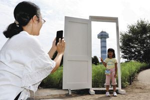 コスモス畑に登場した白いドアの前で撮影する親子＝海津市海津町の木曽三川公園センターで
