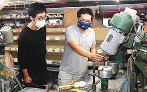 宮吉製陶の成形用ローラーマシンを紹介する宮吉宏樹専務（右）＝小松市吉竹町で