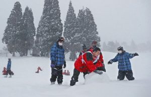 長崎県から修学旅行で訪れ、真っ白なゲレンデで雪遊びを楽しむ学生ら＝郡上市のスノーウェーブパーク白鳥高原で
