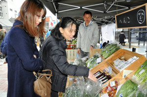 地産の食材や加工品を手に取る客ら＝伊賀市の伊賀鉄道上野市駅前広場で