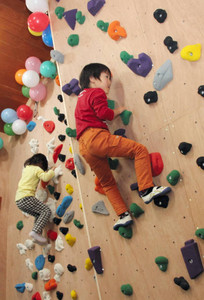 ブロックに手足をかけて壁を登る子どもたち＝瑞浪市釜戸町の市自然ふれあい館で