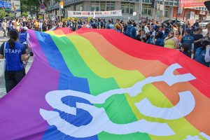 ７月上旬、ソウルで行われた「クィア・パレード」。正面奥には反対するキリスト教団体が「同性愛の罪を悔い改めよ」との横断幕を掲げている