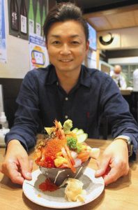 「海鮮のせすぎ丼」を紹介する泉社長＝四日市市諏訪栄町で