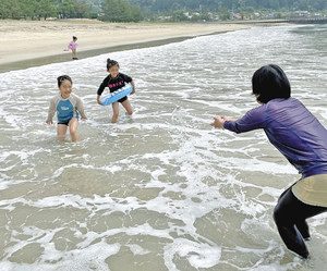 海水をかけあって遊ぶ子どもたち＝尾鷲市の三木里海水浴場で