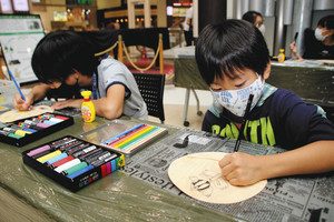 間伐材のうちわにイラストを描く子どもたち＝浜松市東区天王町のイオンモール浜松市野で