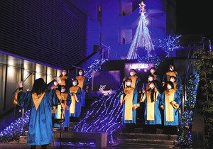 イルミネーションの前で賛美歌を披露するゴスペルチーム＝飯田市のほんまちプラザで