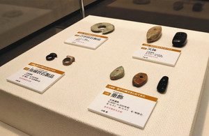 展示スペースの中央に並ぶ縄文時代のアクセサリーとみられる石製品＝いずれも金沢市上安原南で